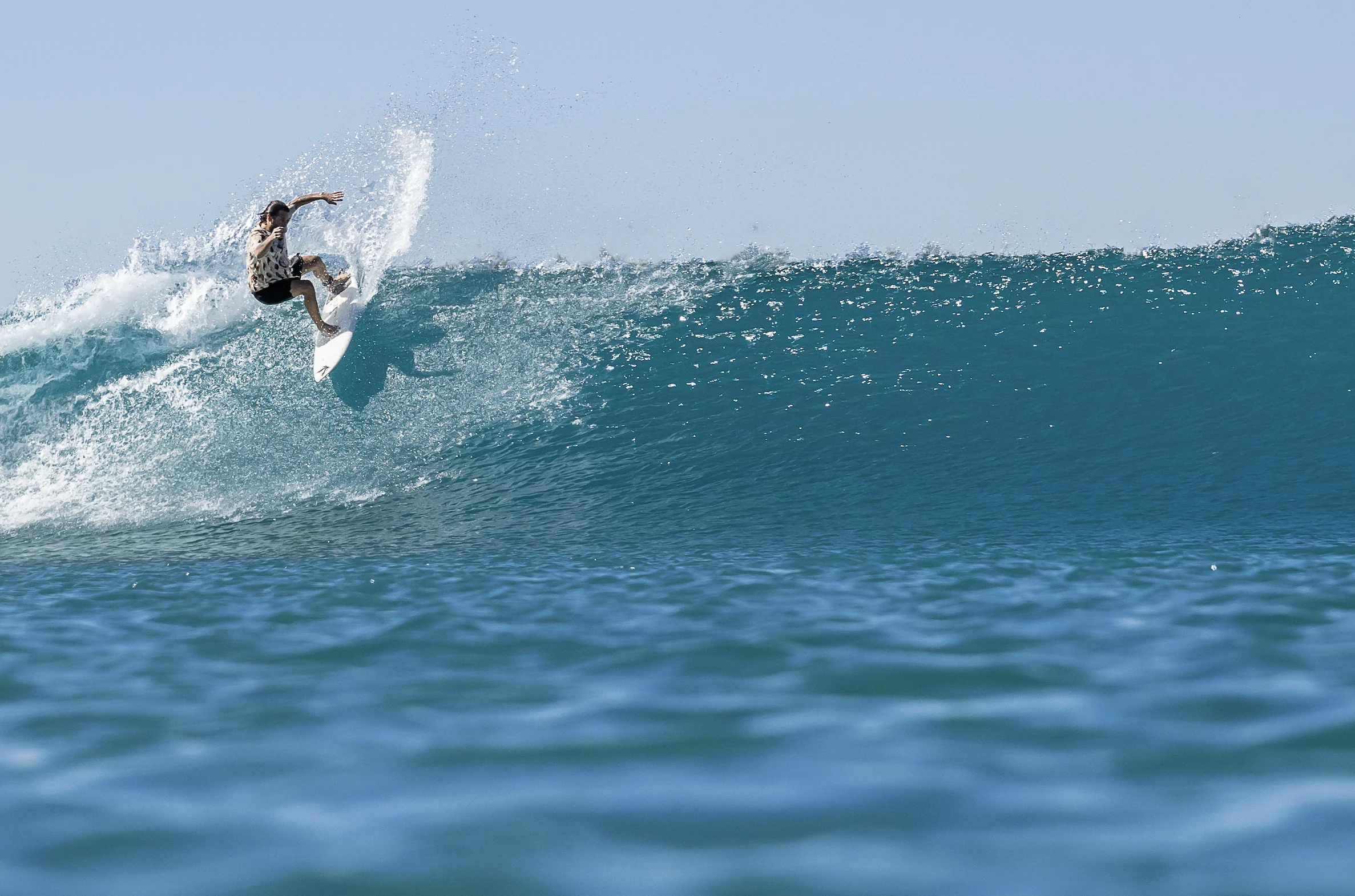 Jon Amezcua surfing, carving high on the face of a clean blue wave